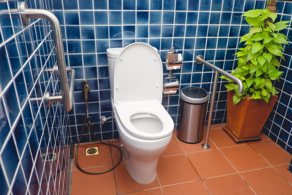 Public restroom for disabled and elderly people, handicap toilet with grab bars on the walls
