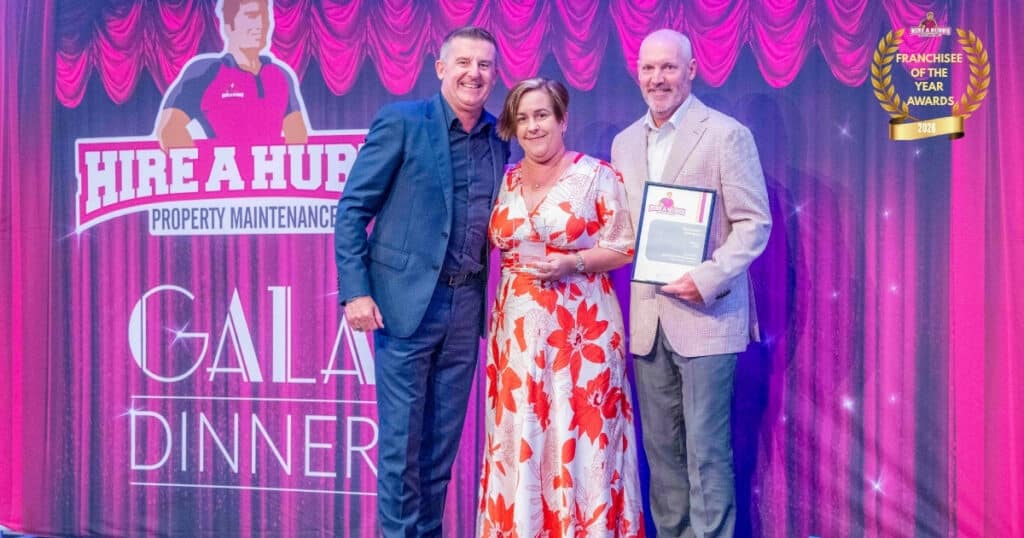 Russell and Michelle Hampton of Hire A Hubby Bayview receiving the National Franchisee of the Year award on stage at the 2026 Gala Dinner