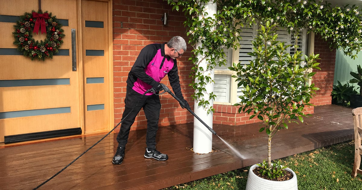 Hire A Hubby handyman pressure cleaning a timber deck at a home decorated for Christmas